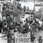 A photo of the 1973 Pride march in Minneapolis showing 100 people marching on Nicollet Mall led by a "Gay Pride" banner.