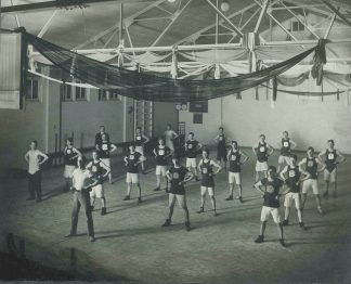 Burroughs Employee Calisthenics Club engaging in group exercises led by instructor, circa 1910.