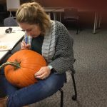 Emily begins to carve after using the stencil to mark the image on the pumpkin.