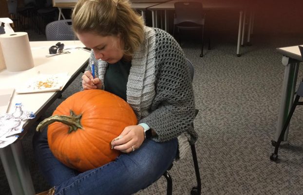 Emily begins to carve after using the stencil to mark the image on the pumpkin.