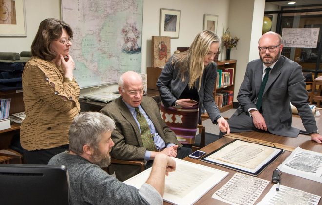 Representatives from Christie’s with Maggie Ragnow at left examine the Bell Library’s print of the Waldseemüller map