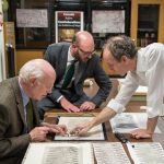Representatives from Christie's examine the Bell Library's print of the Waldseemüller map