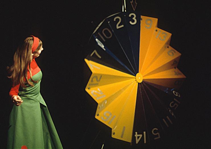 Woman in green and red looking at yellow and black set piece in opera