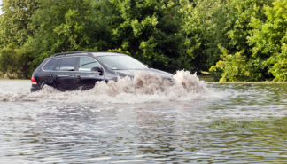 Photo of car driving through flood water.