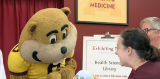 Goldy Gopher inspects a model human skull at the UMN Health Sciences Library's booth.