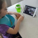 A young child watches virtual StoryTime on a tablet.