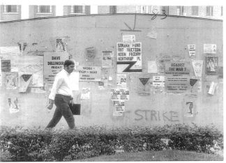 A man walks past posters and fliers anti-war messages and support for the student strike on campus. Bill Tilton papers, University Archives, University of Minnesota, Twin Cities.