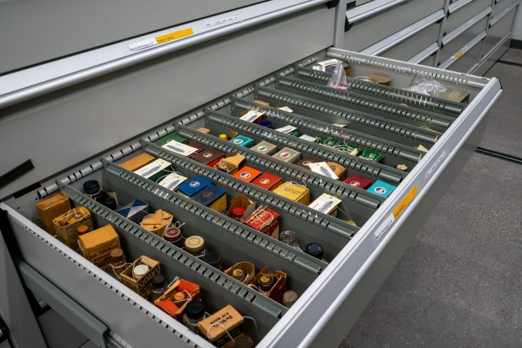 A metal drawer full of brightly colored boxes of pharmaceutical products is pulled out for viewing.