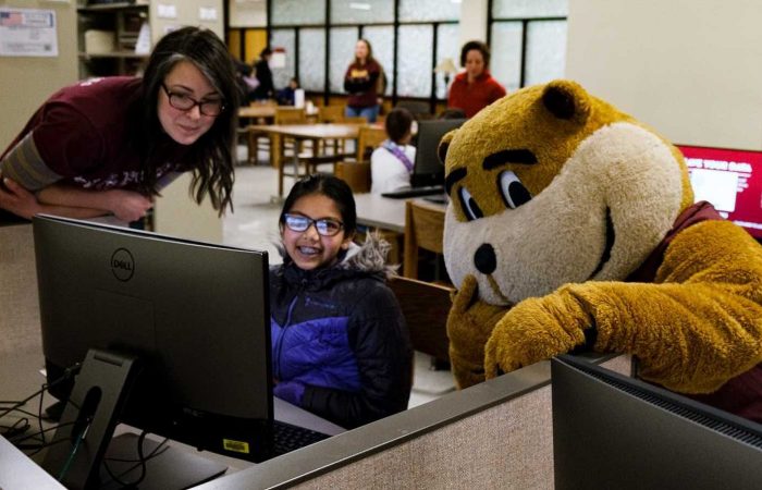 Alicia Kubas, left, and Goldy help out a student on History Day at Wilson Library.