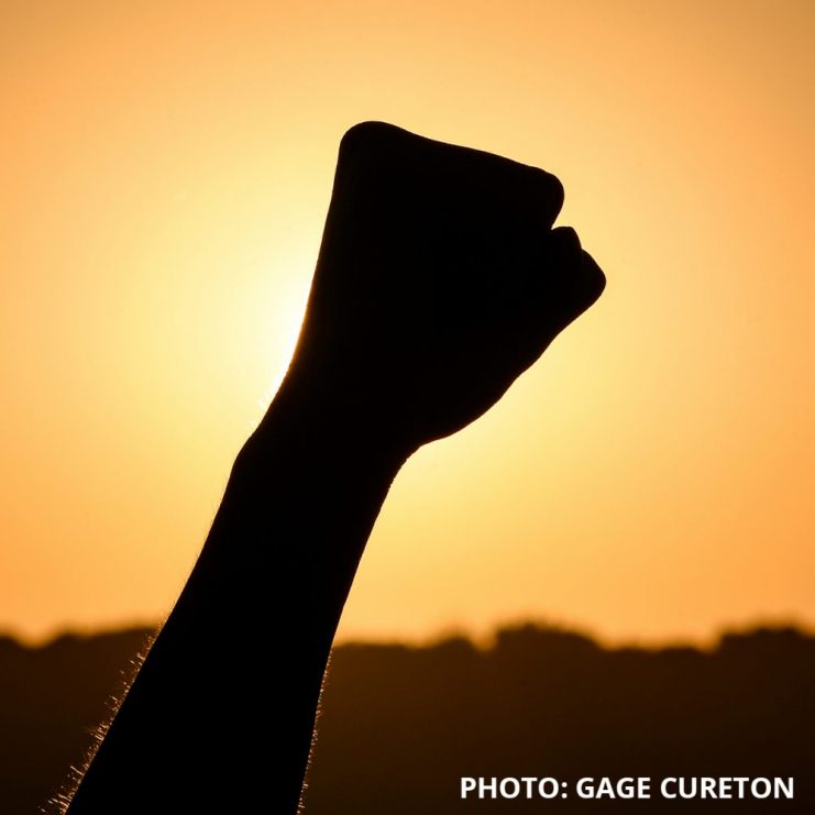 Photo by Gage Cureton of raised fist against the sunset sky