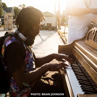 Photo by Brian Johnson of a person playing a piano outdoors