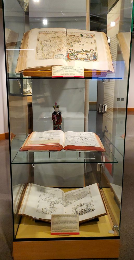 Exhibit case containing three large atlases.