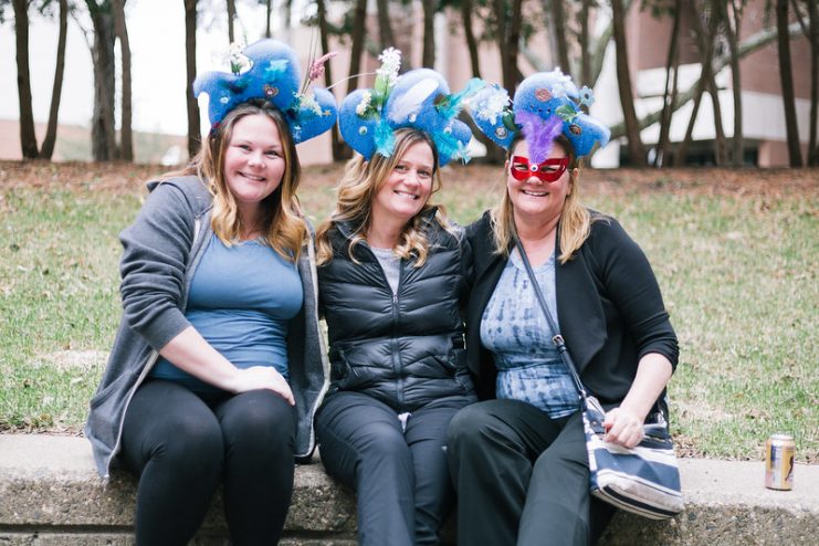Three smiling guests with costume hats they made at the event