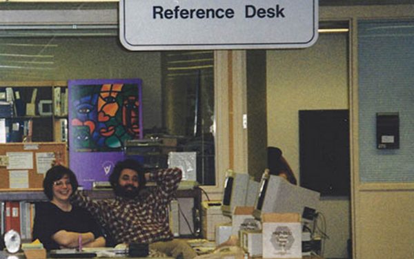 Person sitting at computers under a sign that says Reference Desk.