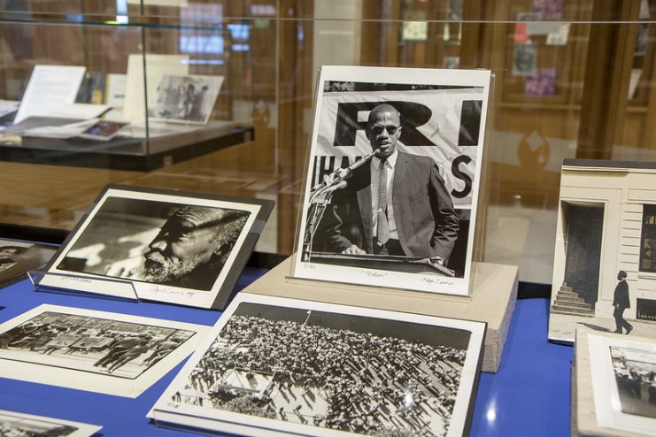 Exhibit case with a selection of photos by Adger Cowans, including a central photo of Malcolm X.