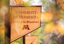 Pole banner that reads "University of Minnesota Driven to Discover" with autumn foliage visible in background