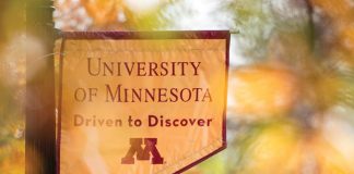 Pole banner that reads "University of Minnesota Driven to Discover" with autumn foliage visible in background