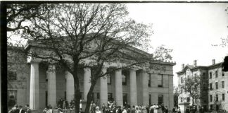 Black and white image from the University Archives of Burton Hall, a columned building. Students appear in the foreground milling about.