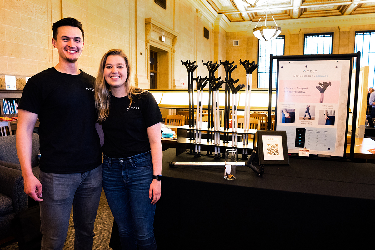 Steven and Morgan standing in front of their poster for Telo Walking Canes at Founders Day. Walking cane prototypes displayed on table behind them