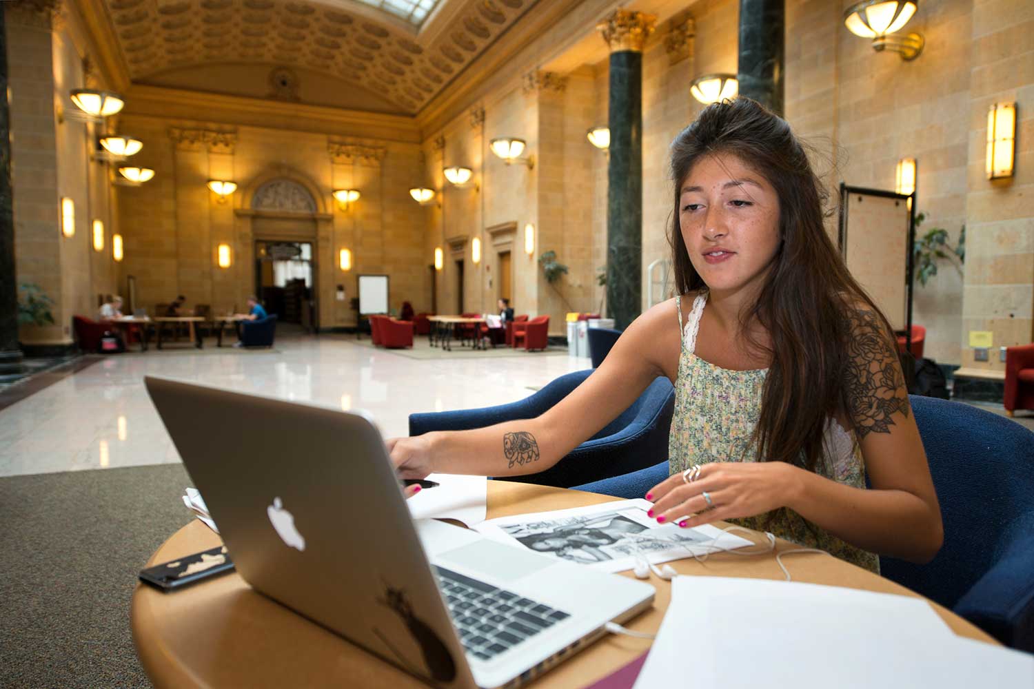 A student studies at table with a laptop computer inside Walter Library's Great Hall.