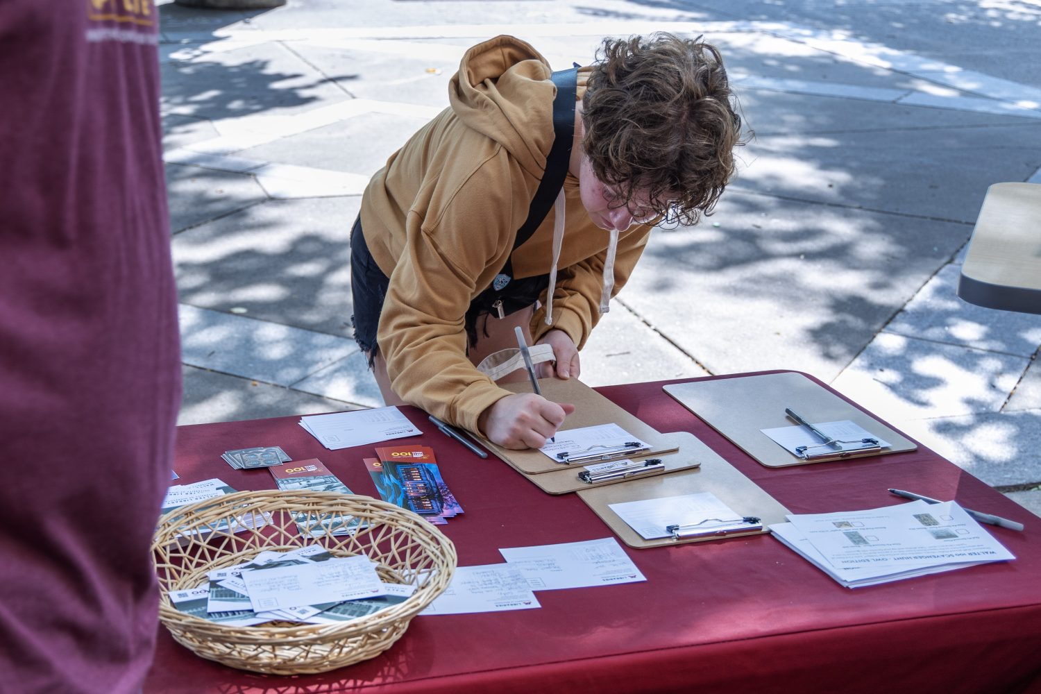 A student writes a postcard at the Libraries' table outside Walter Library. (Photo/Adria Carpenter)